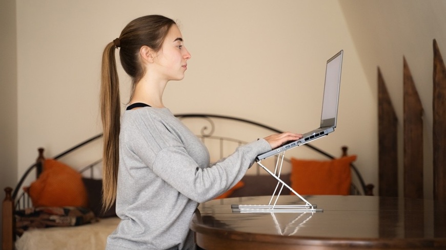 Žena píše na notebooku ve stoje