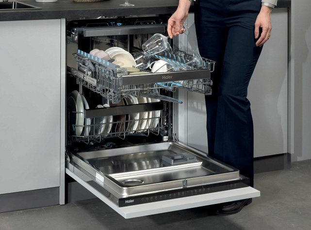 Vestavná myčka Haier Xynergy: Mimořádná úspora s tepelným čerpadlem osoba vkládá sklenici do vestavné myčky Haier Xynergy