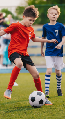 chlapci hrající fotbal na venkovním fotbalovém hřišti