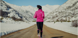 žena běžící v zimním sportovním oblečení v zasněžené přírodě