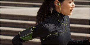 běžící žena se sluchátky v uších a mobilem ve sportovním obalu na paži